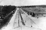 KL Dachau – pohľad na baraky, v ktorých bývali väzni, plot z ostnatého drôtu, cez ktorý prechádzal elektrický prúd s vysokým napätím, vedľa barakov väzni; apríl 1945. (AIPN)